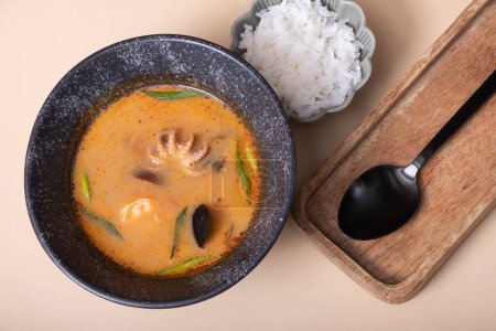 Tom yum soup and rice on a gray background angle view.