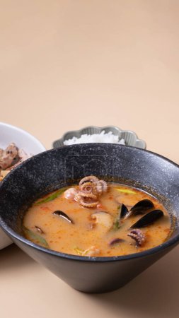 Tom yam soup with seafood and bowl with rice, veal and vegetables and angle view