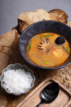 Photo for Tom yum soup with seafood and rice on wooden table angle view. - Royalty Free Image