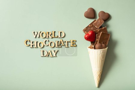 World chocolate day text with chocolate flat lay, top view on pastel green background.