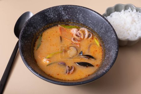 Tom yum soup and rice on a gray background angle view.
