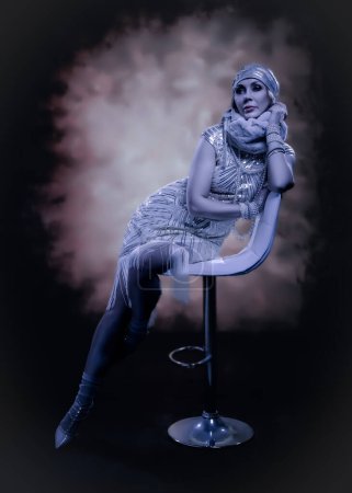 Foto de Elegante mujer de moda vestida en estilo retro art deco de los años 20. Retrato de una sensual mujer de cincuenta años. Foto teñida. - Imagen libre de derechos
