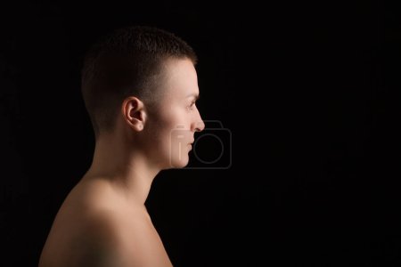 Téléchargez les photos : Portrait de jeune femme aux cheveux courts et à l'épaule nue, sur fond de boulangerie noir - en image libre de droit