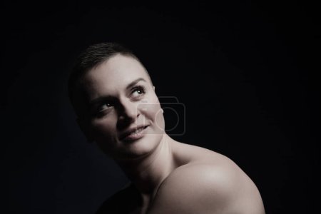 Photo for Portrait of young woman with short hair and bare shoulder, on black bakground - Royalty Free Image