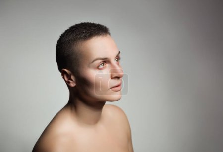 Photo for Portrait of young woman with short hair and bare shoulder, on grey background - Royalty Free Image
