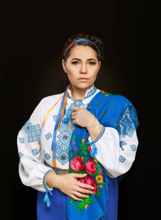 Photo for Beautiful Ukrainian woman in national costume. Attractive Ukrainian woman wearing in traditional Ukrainian embroidery vyshyvanka, at black background. - Royalty Free Image