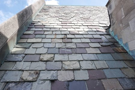 Weathered slate tiles on the roof of a historic building. Slate is highly valued as a traditional building material.