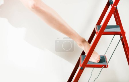 Foto de Joven rubia pierna de mujer en medias en escalera roja paso en fondo blanco - Imagen libre de derechos