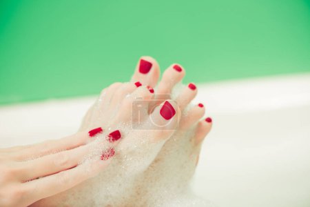 Foto de Mujer joven manos y pies cubiertos de espuma en el interior de baño blanco - Imagen libre de derechos