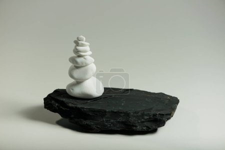 Téléchargez les photos : Pierres lisses blanches équilibrées sur une pierre plate noire - en image libre de droit