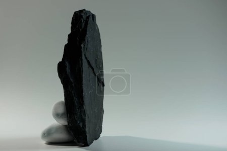Téléchargez les photos : Petites pierres blanches lisses derrière une grande pierre noire plate - en image libre de droit