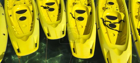 Foto de Primer plano de varios kayaks de color amarillo brillante flotando en el agua de mar turquesa. - Imagen libre de derechos
