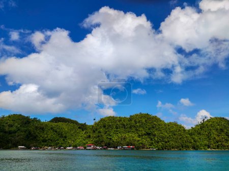 Foto de Una pintoresca escena de una majestuosa montaña que se eleva junto a un mar sereno y azul donde anida una pintoresca comunidad costera. - Imagen libre de derechos