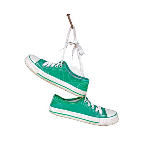 Foto de Par de zapatillas verdes viejas colgando en clavo rústico aislado sobre fondo blanco - Imagen libre de derechos