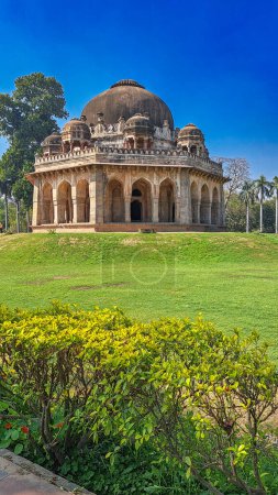 Das antike Grab von Muhammad Shah Sayyid im Lodhi Garden in Neu Delhi. Das Grab ist ein architektonisches Wunder mit einer großen Kuppel und aufwändigen Schnitzereien an der Fassade. Saftiges grünes Gras und lebendige gelb-grüne Sträucher