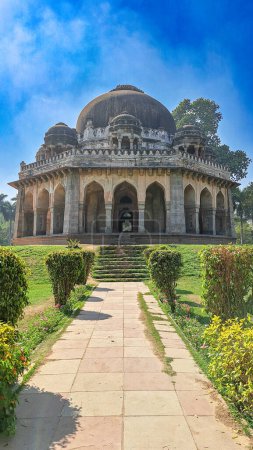 Das antike Grab von Muhammad Shah Sayyid im Lodhi Garden in Neu Delhi. Das Grab ist ein architektonisches Wunder mit einer aufwändigen Schnitzerei an Fassade und großer Kuppel. Saftiges grünes Gras und lebendige gelb-grüne Sträucher