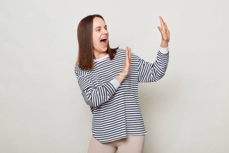 Photo for Positive optimistic brown haired woman wearing striped shirt posing isolated over gray background standing with raised palms screaming with happiness festive mood. - Royalty Free Image