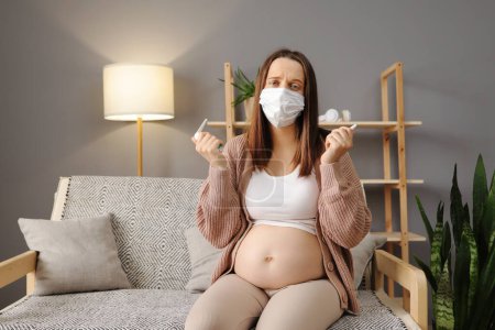 Photo for Sick ill unhealthy Caucasian pregnant woman sitting on sofa at home holding nasal spray and spray for inhalation taking care of her health during pregnancy flu - Royalty Free Image