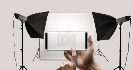 Téléchargez les photos : Deux mains tenant un Smartphone mobile et prendre une photo d'un studio photo - en image libre de droit
