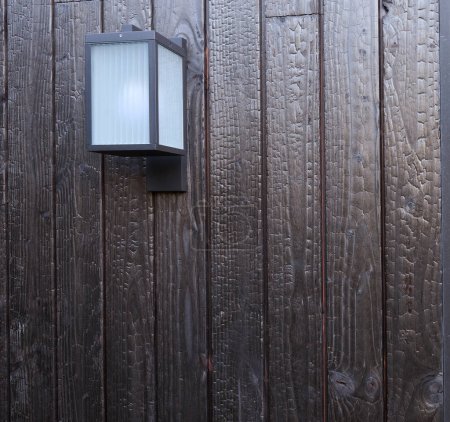 Lampe extérieure moderne sur mur de bois brûlé