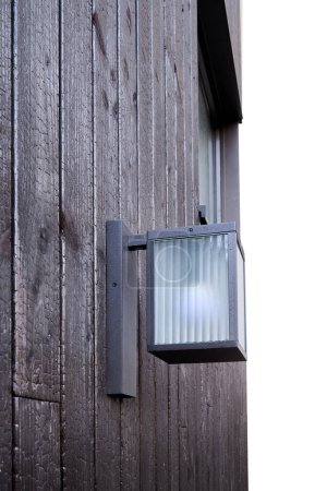 Modern external lamp on burned wood wall