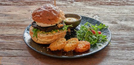 Plate with Vegetarian burger and rosti on textured wooden table