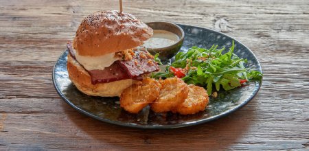 Assiette avec hamburger de porc et rosti sur table en bois texturé