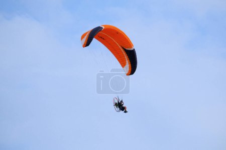 Foto de Italia, Sicilia, Marina di Ragusa (provincia de Ragusa); 16 de septiembre de 2023, hombre volando en un parapente motorizado - EDITORIAL - Imagen libre de derechos