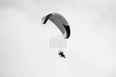 Foto de Italia, Sicilia, Marina di Ragusa (provincia de Ragusa); 16 de septiembre de 2023, hombre volando en un parapente motorizado - EDITORIAL - Imagen libre de derechos