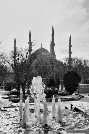 Foto de Turquía, Estambul, una fuente y la Mezquita Imperial Sultanahmet, también conocida como la Mezquita Azul, mientras nieva (construida en el siglo XVII por el arquitecto Mehmet) - Imagen libre de derechos