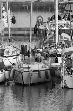 Foto de Italia, Sicilia, Mar Mediterráneo, Marina di Ragusa (Provincia de Ragusa); 16 de abril de 2024, mujer en un velero en el puerto - EDITORIAL - Imagen libre de derechos
