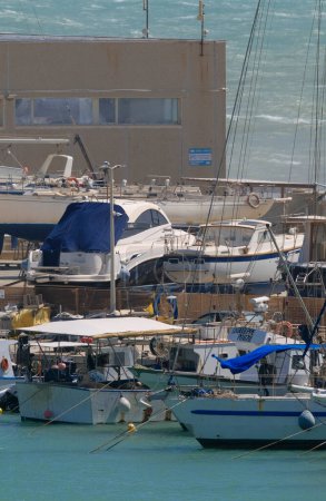 Foto de Italia, Sicilia, Marina di Ragusa (provincia de Ragusa), 17 de abril de 2024, barcos de pesca locales y yates de lujo en tierra en el puerto - EDITORIAL - Imagen libre de derechos