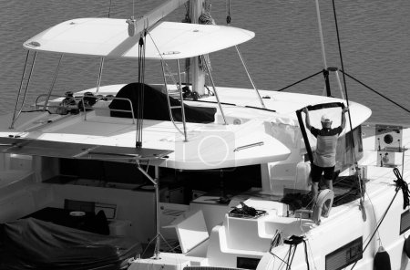Foto de Italia, Sicilia, Mar Mediterráneo, Marina di Ragusa (Provincia de Ragusa); hombre en un catamarán velero en el puerto - Imagen libre de derechos