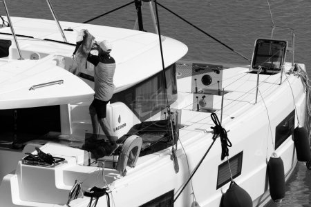 Foto de Italia, Sicilia, Mar Mediterráneo, Marina di Ragusa (provincia de Ragusa); 21 de abril de 2024, hombre en un velero catamarán en el puerto - EDITORIAL - Imagen libre de derechos