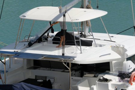 Foto de Italia, Sicilia, Mar Mediterráneo, Marina di Ragusa (provincia de Ragusa); 21 de abril de 2024, hombre en un velero catamarán en el puerto - EDITORIAL - Imagen libre de derechos