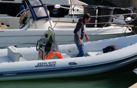 Foto de Italia, Sicilia, Mar Mediterráneo, Marina di Ragusa (provincia de Ragusa); 21 de abril de 2024, hombre en un barco de goma en el puerto - EDITORIAL - Imagen libre de derechos