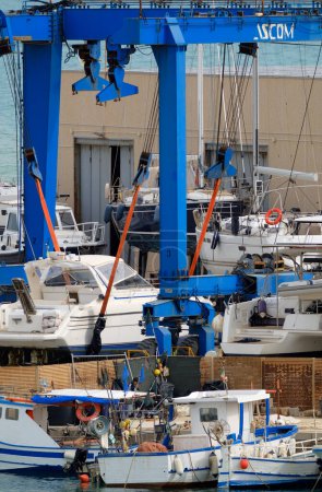 Foto de Italia, Sicilia, Marina di Ragusa (provincia de Ragusa), 26 de abril de 2024, barcos de pesca locales y yates de lujo en tierra en el puerto - EDITORIAL - Imagen libre de derechos