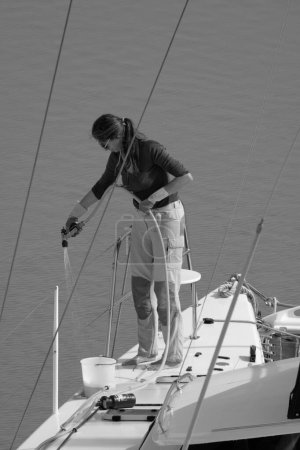 Foto de Italia, Sicilia, Mar Mediterráneo, Marina di Ragusa (Provincia de Ragusa); 1 de mayo de 2024, mujer en un velero catamarán en el puerto - EDITORIAL - Imagen libre de derechos