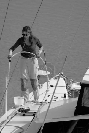 Foto de Italia, Sicilia, Mar Mediterráneo, Marina di Ragusa (Provincia de Ragusa); 1 de mayo de 2024, mujer en un velero catamarán en el puerto - EDITORIAL - Imagen libre de derechos