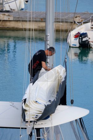 Foto de Italia, Sicilia, Mar Mediterráneo, Marina di Ragusa (Provincia de Ragusa); 10 de mayo de 2024, hombre en un velero catamarán en el puerto - EDITORIAL - Imagen libre de derechos