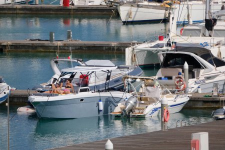 Foto de Italia, Sicilia, Mar Mediterráneo, Marina di Ragusa (Provincia de Ragusa); 12 de mayo de 2024, pareja en un yate de lujo en el puerto - EDITORIAL - Imagen libre de derechos