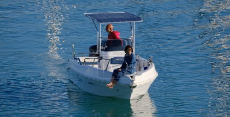 Foto de Italia, Sicilia, Mar Mediterráneo, Marina di Ragusa (Provincia de Ragusa); 12 de mayo de 2024, pareja en un barco a motor en el puerto - EDITORIAL - Imagen libre de derechos