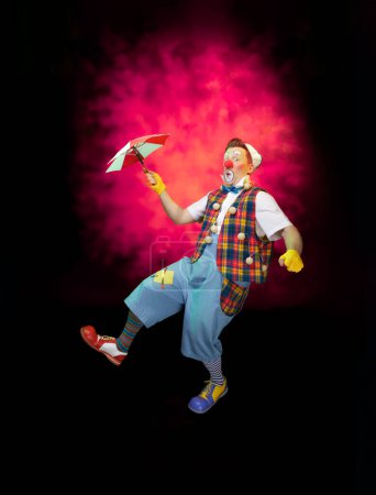 Téléchargez les photos : Un clown drôle avec une expression joyeuse souriante, à fond coloré - en image libre de droit