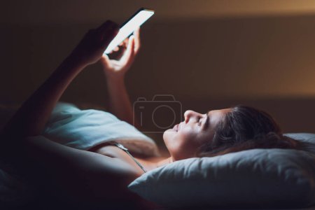 Foto de Mujer de noche en la cama con teléfono. Foto de alta calidad - Imagen libre de derechos