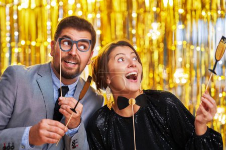 Téléchargez les photos : Couple sur l'or avec accessoires photomaton sur la fête. Photo de haute qualité - en image libre de droit