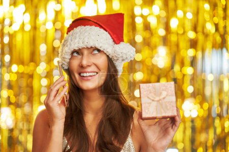 Foto de Mujer sobre fondo dorado en sombrero de Santa Claus con teléfono. Foto de alta calidad - Imagen libre de derechos