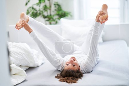 Nette Frau im Bett entspannen oder Yoga machen. Hochwertiges Foto