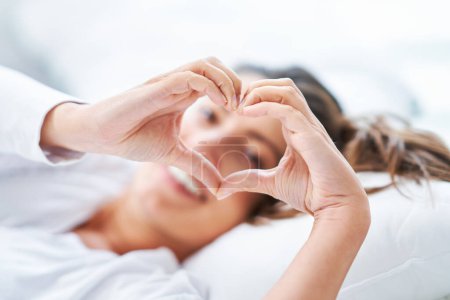 Photo for Young nice woman on the bed showing heart. High quality photo - Royalty Free Image