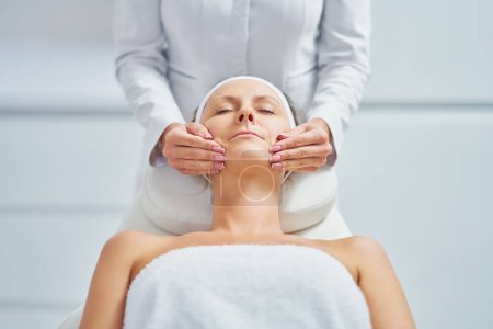 Téléchargez les photos : Young nice woman having face massage in spa. High quality photo - en image libre de droit