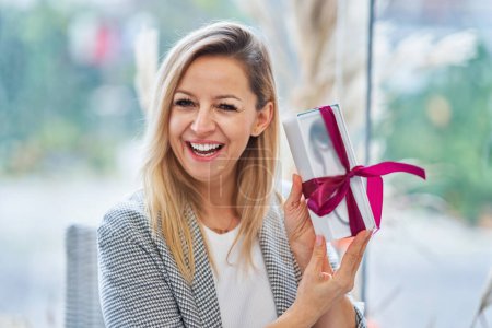Téléchargez les photos : Picture of woman holding a gift in restaurant. High quality photo - en image libre de droit